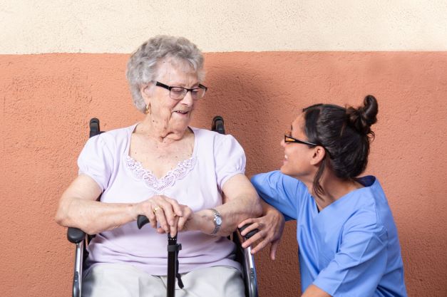 happy-senior-woman-with-walking-stick-wheelchair-with-her-caregiver-home